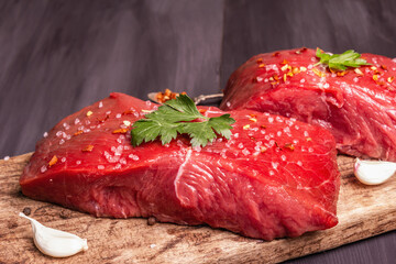 Raw beef steaks on a wooden cutting board