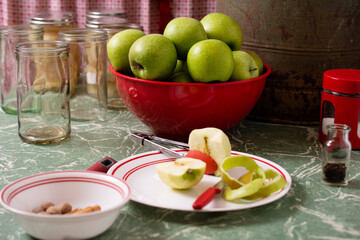 Cut and peeled apple in front of bowl of green apples