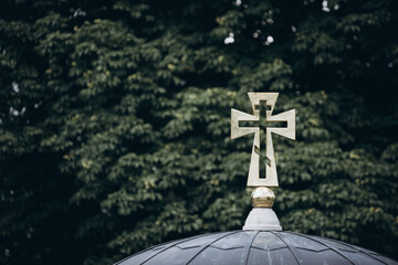 cross on a background of green branches