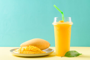 Fresh mango smoothie in a glass and sliced ripe mango fruit on color background, Tropical drink