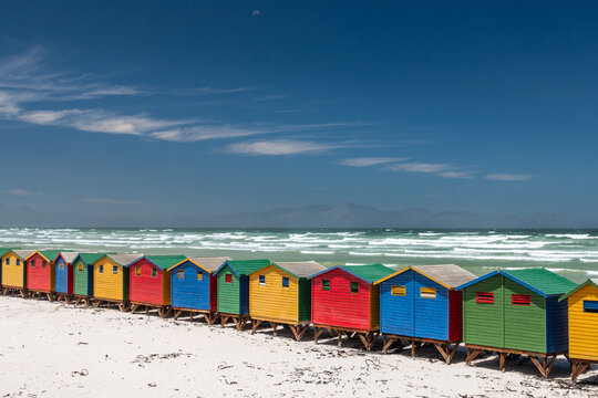 Famous colorful beach houses in Muizenberg near Cape Town, South Africa with Hottentots Holland mountains in the background.