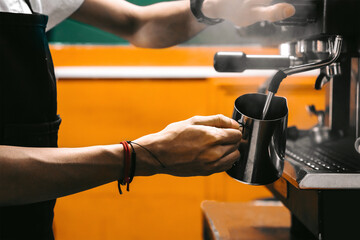hands of a person using a coffee machine filling it with milk.