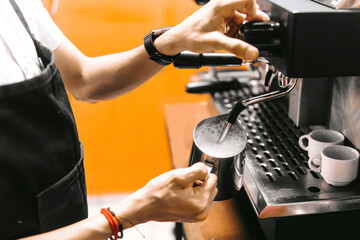 unrecognizable hands of a person using a coffee machine filling it with milk.