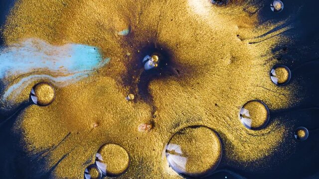 Macro Close Up Shot Of Golden Wet Glitter. Colorful Space Glittering Particle Background. Golden sparkling sand or dust creating abstract cloud formations. Gold industry chemical extraction process.