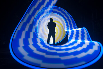 One person standing alone against a Colourful circle light painting as the backdrop