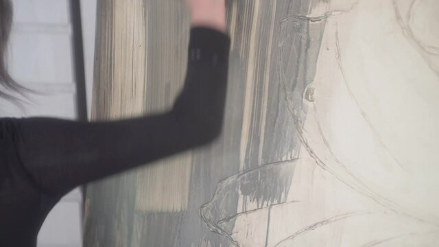 Hispanic Artist Applying Grey Paint On Canvas Using A Paintbrush. - close up