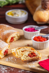 Fatias de pão recheado com calabresa acompanhadas de pastas de tomate, beterraba e iogurte.