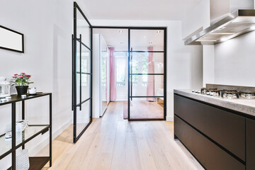 Opened glass door leading into bedroom from stylish kitchen in modern light flat