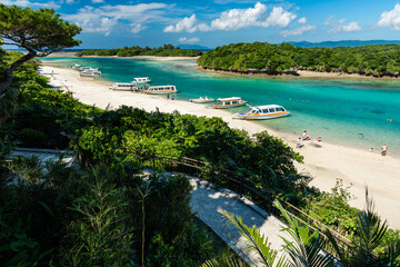 Fototapeta premium Boat tours in the incredible and famous bay of Kabira, floating in its super transparent emerald green waters, vegetation in the background. Amazing scene seen from an lookout point at the park.