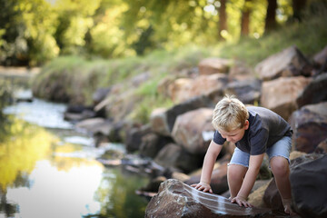 Little boy climbing on and exploring rocks at riverside of Castlereagh River in Coonabarabran, New South Wales, Australia