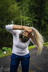 Vertical shot of a Hispanic woman trying to tie her hair on a blurred background