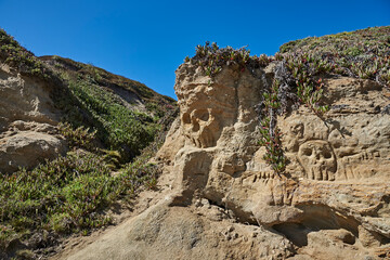 Fototapeta na wymiar Sandstone cliff with Pirate Skull markings on beach