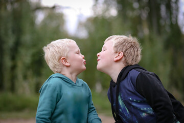 Obraz premium Little boys playing in the bush, being silly pretending to kiss