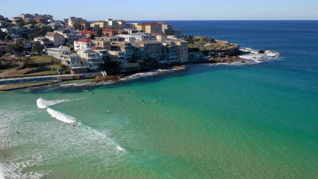 Waterfront Buildings In Ben Buckler Point With Tourist Swimming And Surfing In Bright Blue Sea. Summertime Scene In North Bondi, New South Wales. aerial drone