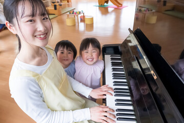 ピアノを弾く保育士と歌う園児