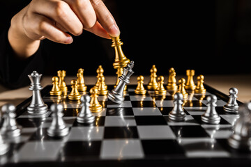 Chess game, hand playing gold king chess piece attack silver king for defeating a king in the game...