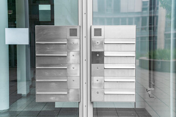 Metal weaving new modern mailboxes in row on an office building with glass door and walls in the afternoon on street in the city