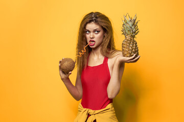 woman with pineapple and coconut cocktail exotic fruits summer lifestyle yellow background