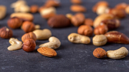 Assortment of various types of nuts on dark background. Cashew, hazelnuts, almonds and Brazil nuts close up. Healthy vegetarian snacks. Protein-containing food. Selective focus.