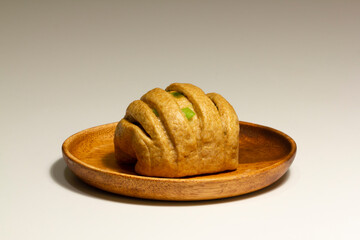 Steamed whole wheat bread with green onions on a wood plate isolated on a white background.