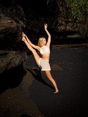 Yoga practice. Slim Caucasian woman practicing Samsahate Hanumanasana, Standing Split Pose. Hamstrings stretching. Strong flexible body. Yoga retreat. Beach in Bali