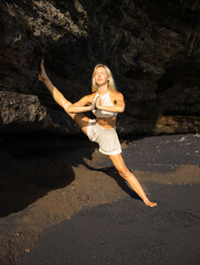 Yoga practice. Attractive Caucasian woman practicing Samsahate Hanumanasana, Standing Split Pose. Hands in namaste mudra. Hamstrings stretching. Flexible body. Yoga retreat. Beach in Bali.