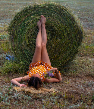 a girl lies on a field and a haystack