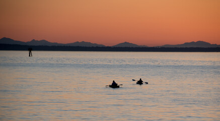 Naklejka premium Watching kayaks at Semiahmoo Bay in the distant from Jorgensen Pier during sunset in Blaine Washington
