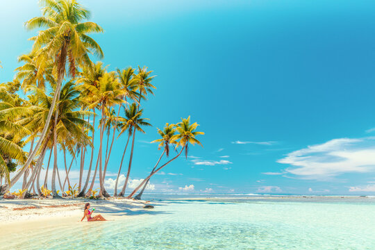 Travel vacation perfect iconic beach with beautiful woman in bikini on private beach island motu relaxing sipping on blue cocktail while sunbathing on French Polynesia travel. Cruise ship destination