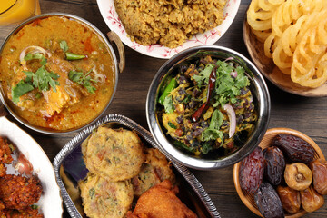 Bengali Iftar Ramadan breakfast spread ripe dates peep fried spicy piaju onion fitter eggplant tanpura potato chop haleem jilapi khichuri rice chana sola curry on rustic wooden table