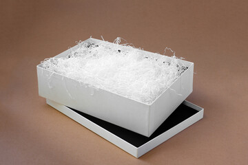 white shredded paper in a white open box on the lid on a paper beige background for protection...