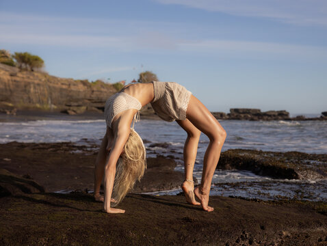 Beach yoga. Young slim woman practicing Chakrasana or Urdhva Dhanurasana, Full Wheel Pose. Upward facing bow pose is a deep backbend. Flexible body. Healthy lifestyle. Bali, Indonesia