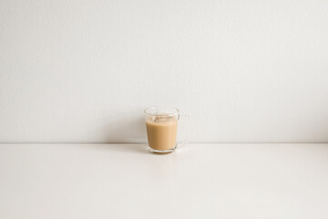 Ice coffee with milk on a white wood table and refreshing look of the drink, with a clean white background.