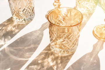 Backdrop with glasses in warm sunlight. Long harsh shadows. Creative abstract background.