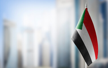 A small flag of Sudan on the background of a blurred background