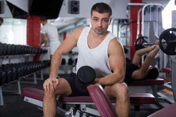 Fototapeta na wymiar Portrait of athletic man exercising with dumbbells in gym