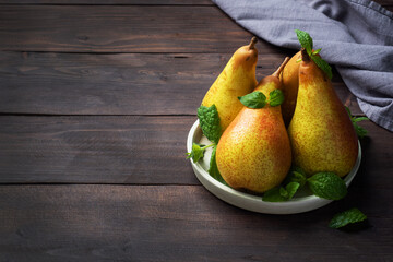 Fresh juicy Pears Conference on dark wooden rustic background. Autumn harvest of ripe fruit. copy space