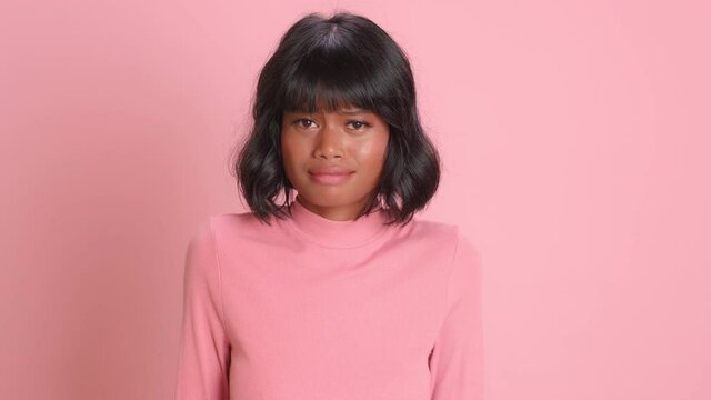 Anxious woman looks with fright and anticipation of something bad happen stares intensely then relaxes and sighs with relief expresses different emotions dressed casually poses over pink background
