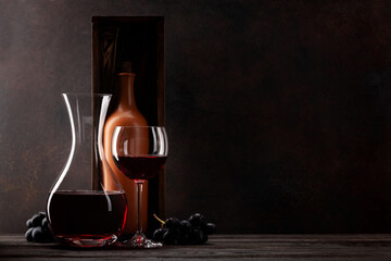 Decanter with red wine, wine bottle in box, grapes and wineglass