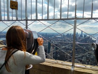 a female tourist looking at the skyscrapers of Manhattan from the observation deck of the Empire...