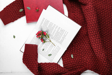 Books with floral decor and sweater on table