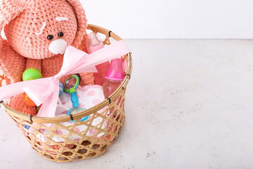 Wicker basket with gifts for baby on light background