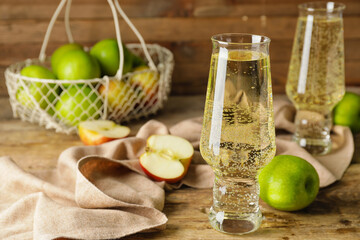 Glasses with cold apple cider and basket on table