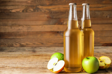 Bottles of apple cider on wooden background
