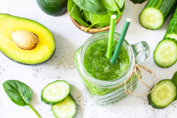Green smoothie recipe. Healthy diet and nutrition, vegan and alkaline drinks. Fresh smoothie with cucumber, avocado and spinach on a gray stone.
