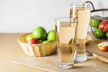 Glasses with apple cider and baskets on table