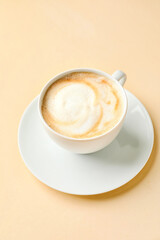 Cup of hot cappuccino coffee on color background