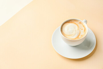 Cup of hot cappuccino coffee on color background