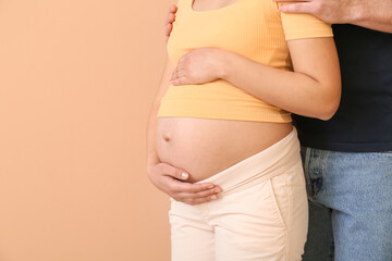 Beautiful pregnant couple on color background