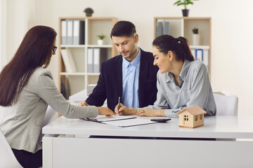 Family couple signing purchase guarantee agreement for new house apartment at real estate agency....